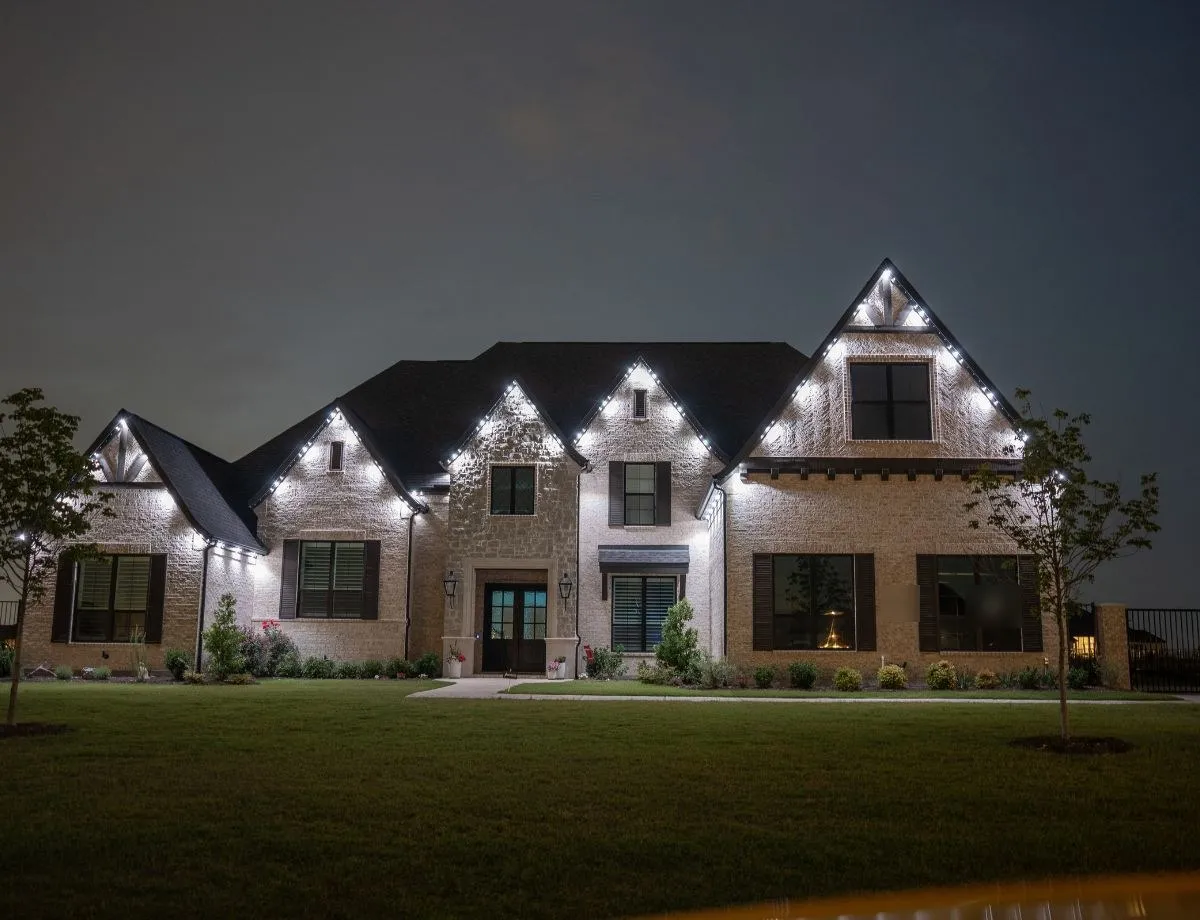 Stone home with bright white gable-line lighting at night