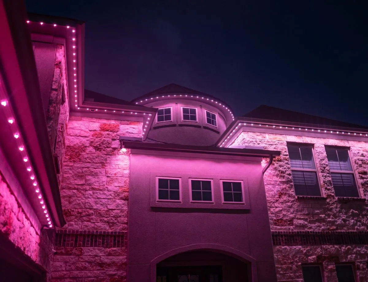 Stone home with bright pink roofline lights