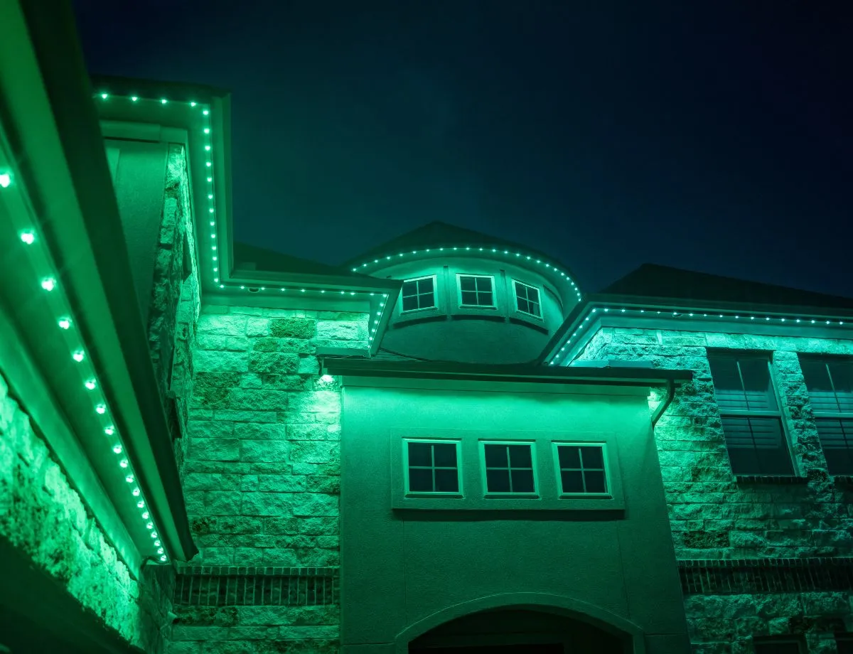 Stone home with a green-lit second story and roofline
